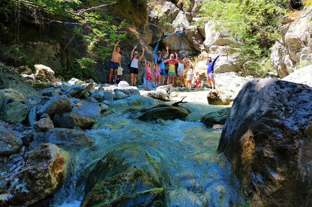 A multi-generational family exploring a waterfall recommended to them by their tour operator MAMAKITA.